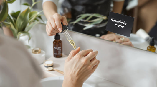 Person applies botanical serum in bright bathroom, 'Natuurlijke kracht' note on mirror