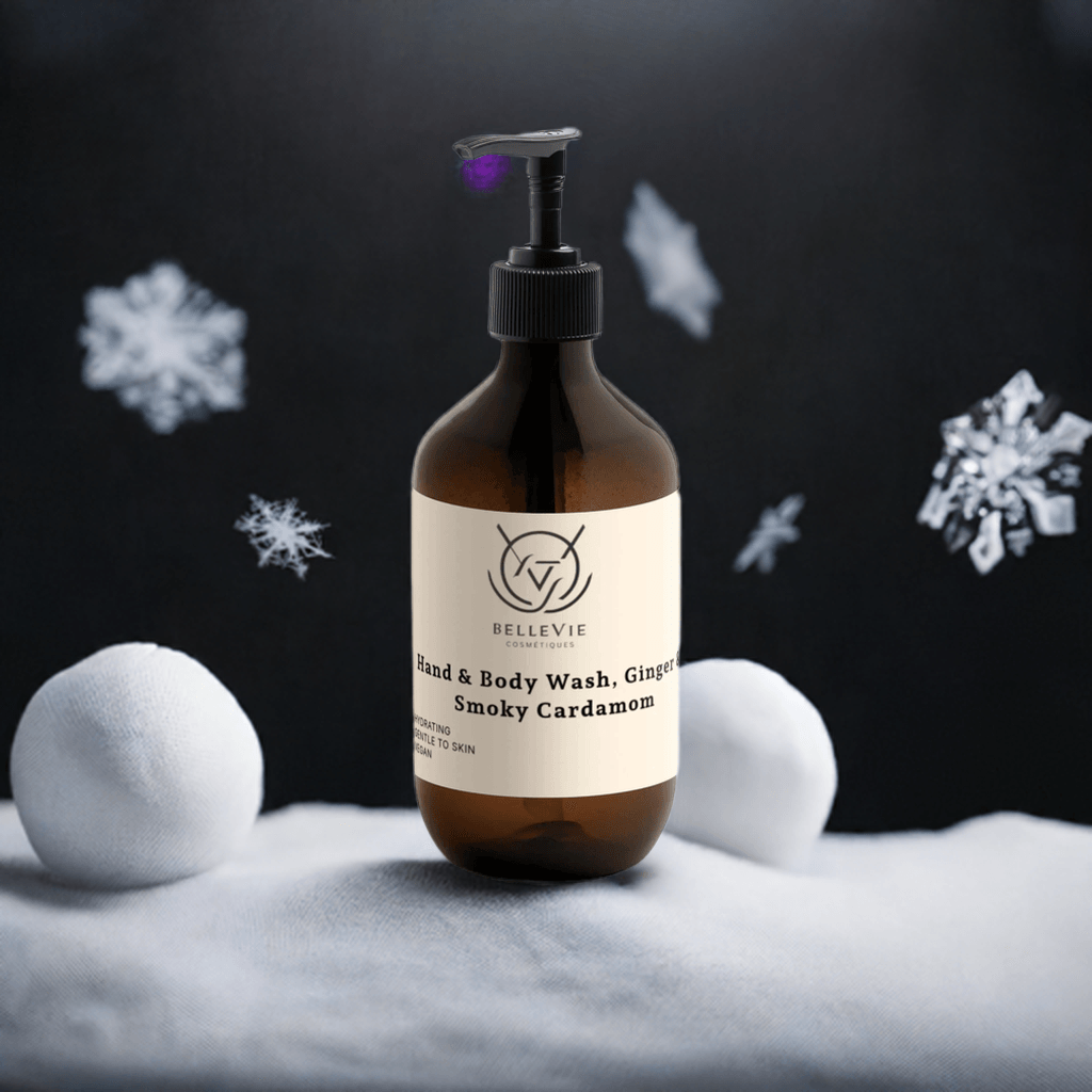 BelleVie Ginger & Smoky Cardamom Body Wash 490ml amber pump bottle surrounded by falling snow on dark background – sulfate-free vegan body wash