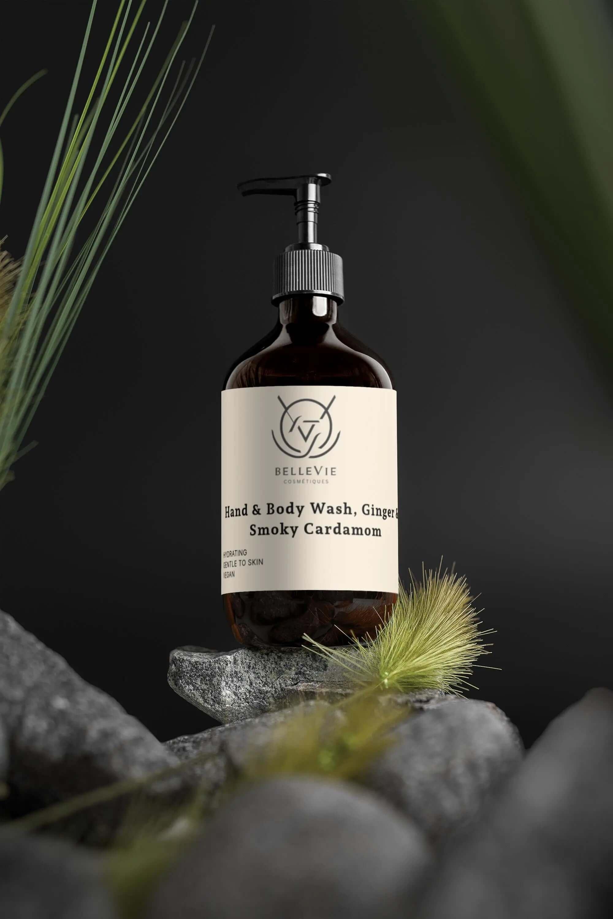 BelleVie Smoky Cardamom Hand & Body Wash 490ml amber pump bottle on stone with tropical grass and dark botanical background – COSMOS Natural certified, vegan, EU-made