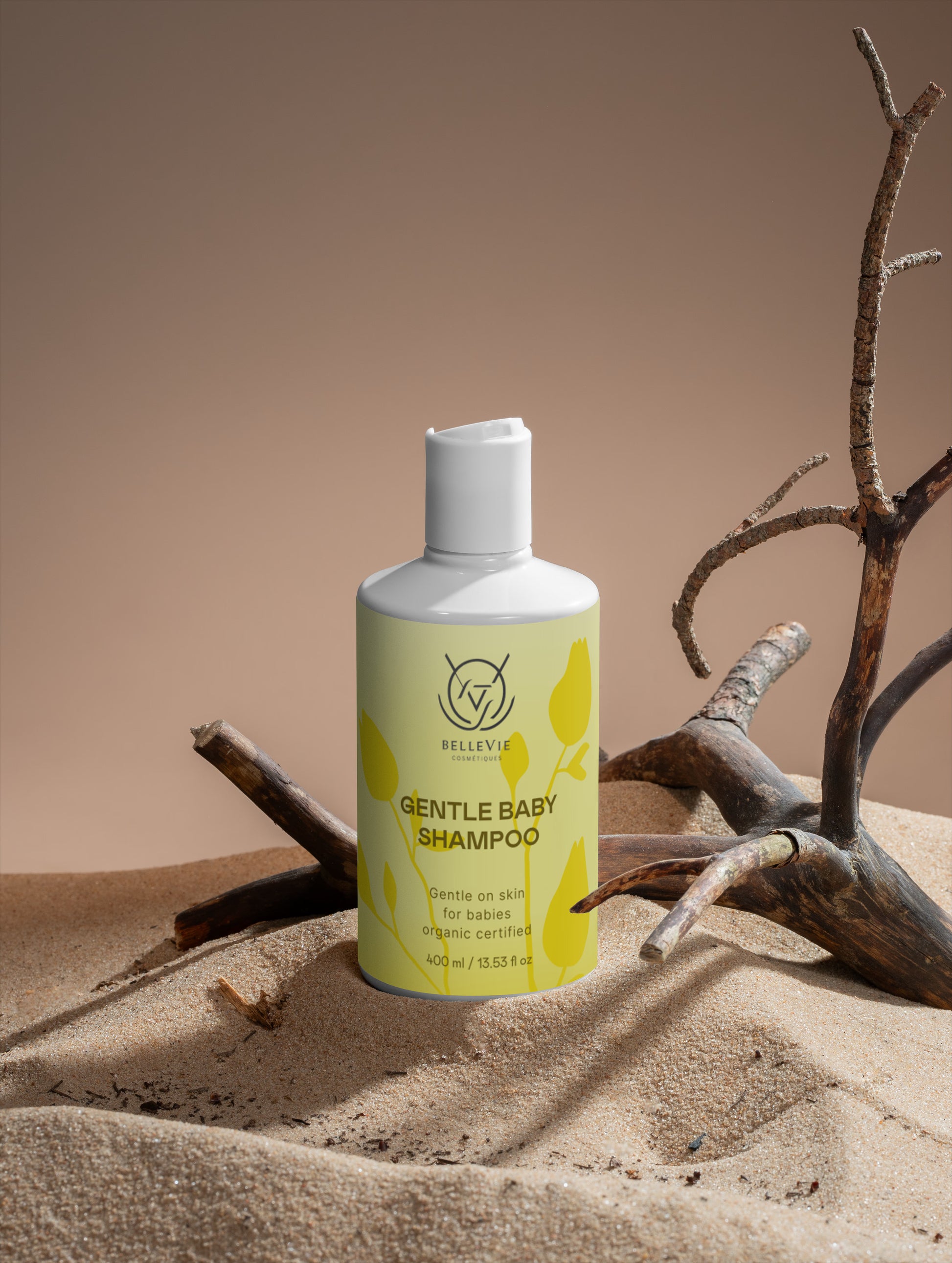 Bellevie baby shampoo on a sandy surface with driftwood