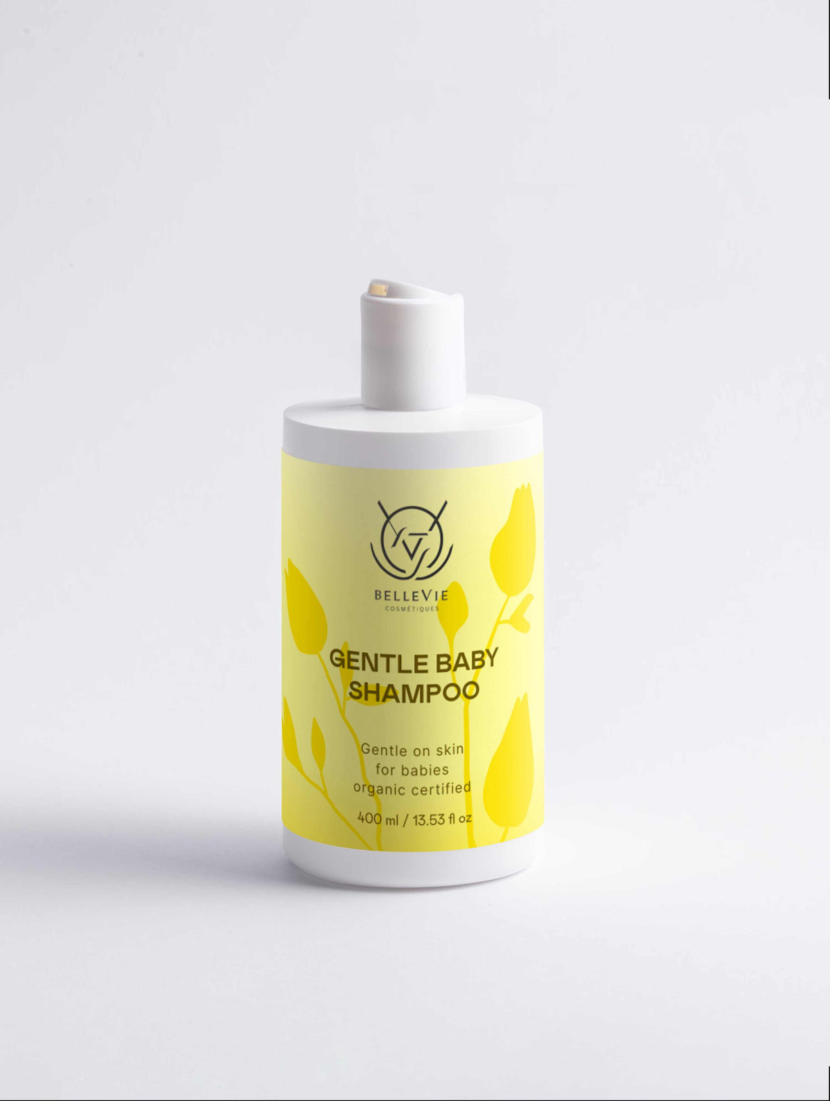 Gentle Baby Shampoo in a white plastic bottle with a bright yellow label, botanical leaf pattern and pump top.