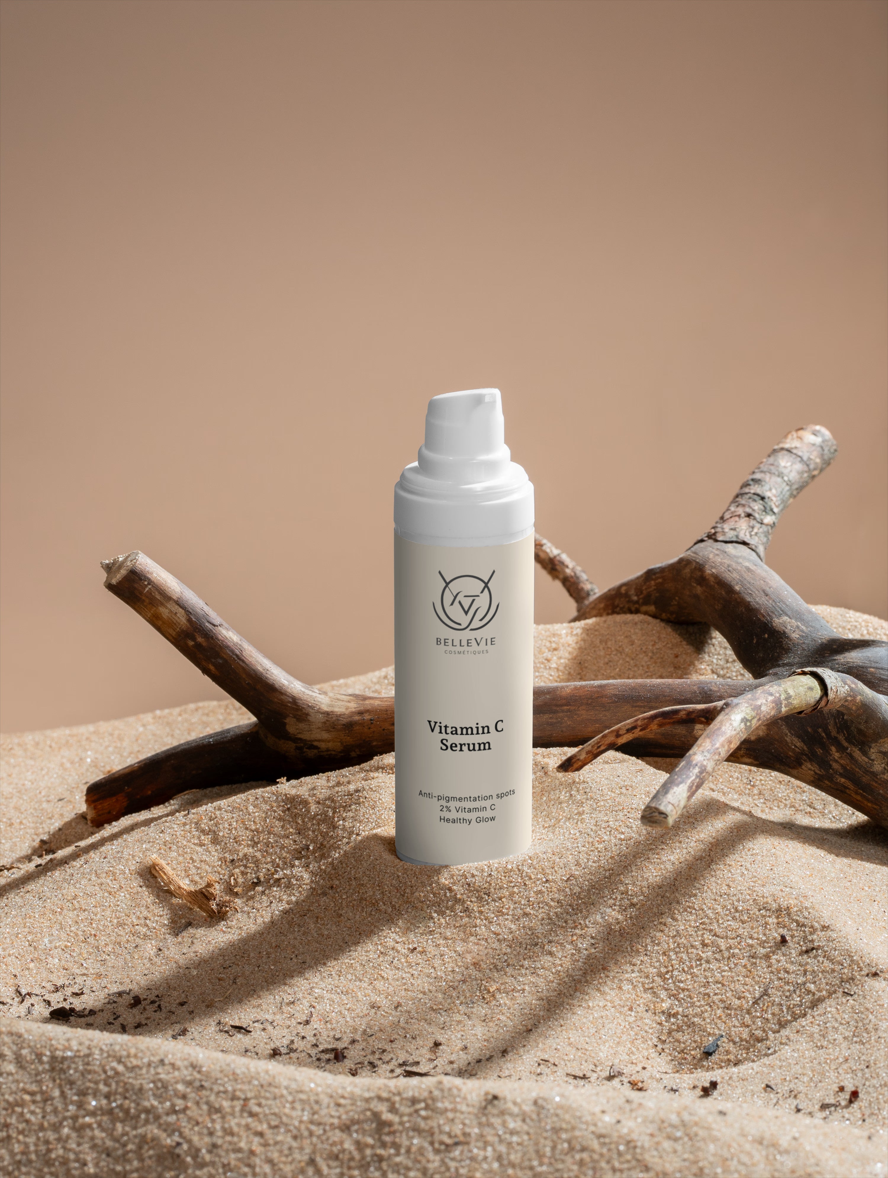 Vitamin C Serum bottle on sand with driftwood