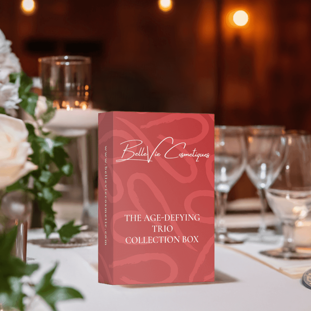 The Age-Defying Trio Collection Box by BelleVie Cosmetiques on a elegantly set table, showcasing luxury anti-aging skincare.