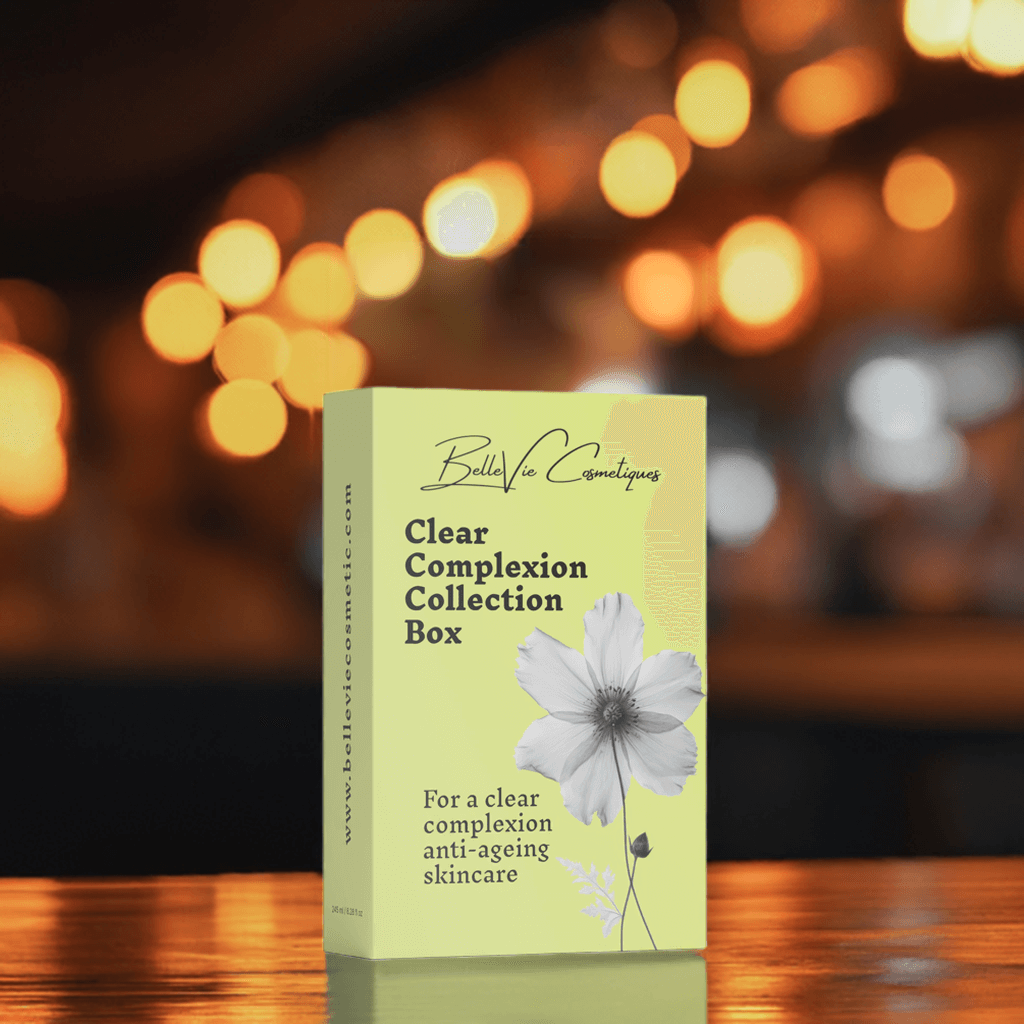 Bella Vie Cosmetiques Clear Complexion Collection Box on a wooden surface with blurred lights in the background