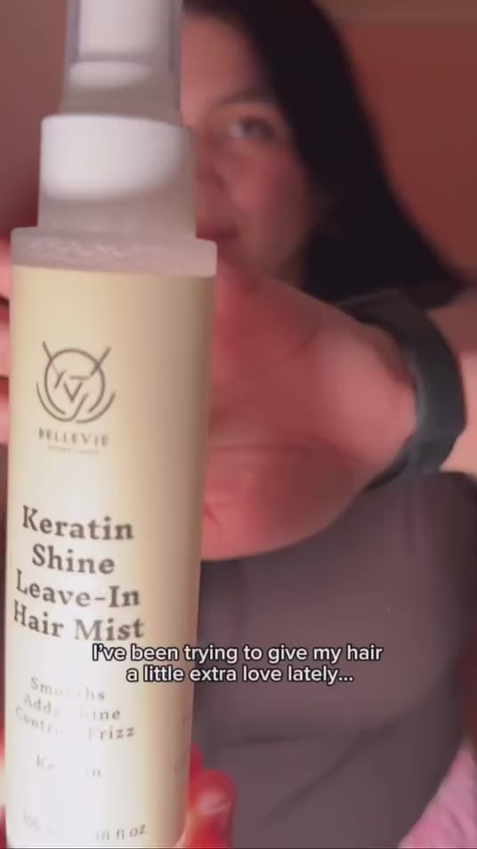 Woman holding BelleVie Keratin Shine Leave-In Hair Mist close to the camera, with her dark hair in the background.
