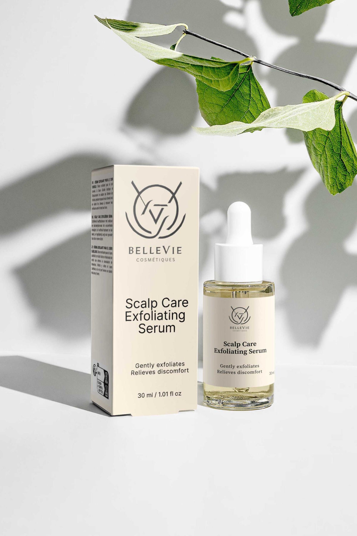 Scalp Renewal Exfoliating Serum in a clear glass dropper bottle beside cream packaging with black text and logo